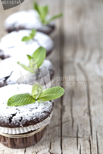 Image of Fresh chocolate dark muffins with sugar powder and mint leaf on 