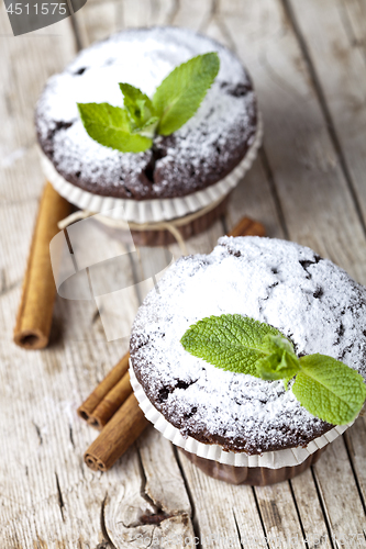 Image of Dark chocolate muffins with sugar powder, cinnamon sticks and mi