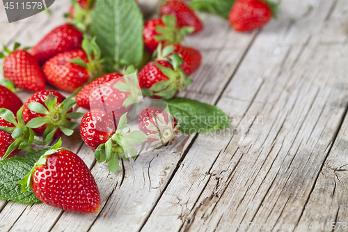 Image of Fresh red strawberries and mint leaves on rustic wooden backgrou