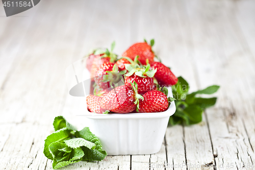 Image of Fresh red strawberries in white bowl and mint leaves on rustic w
