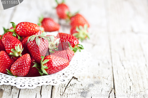 Image of Organic red strawberries on white plate on rustic wooden backgro