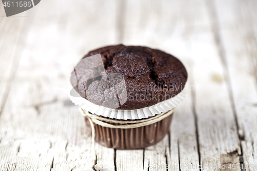 Image of Fresh single chocolate dark muffin on rustic wooden table.