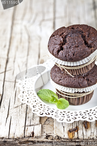 Image of Two fresh dark chocolate muffins with mint leaves on white plate