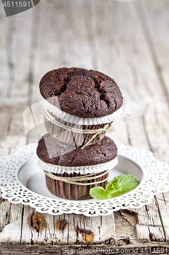 Image of Two fresh dark chocolate muffins with mint leaves on white plate