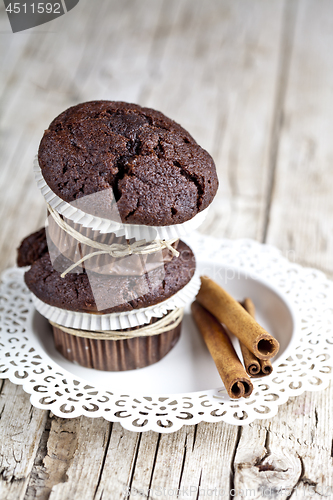 Image of Fresh dark chocolate muffins with cinnamon sticks on white plate