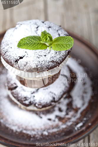 Image of Fresh chocolate dark muffins with sugar powder and mint leaf on 