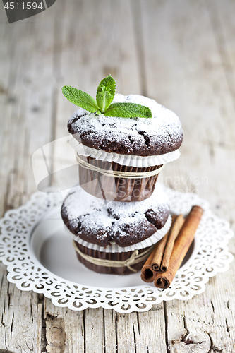 Image of Chocolate dark muffins with sugar powder, cinnamon sticks and mi