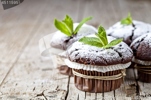 Image of Fresh chocolate dark muffins with sugar powder and mint leaf on 