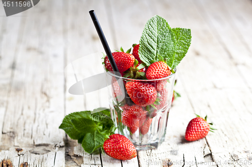Image of Organic red strawberries glass and mint leaves on rustic wooden 