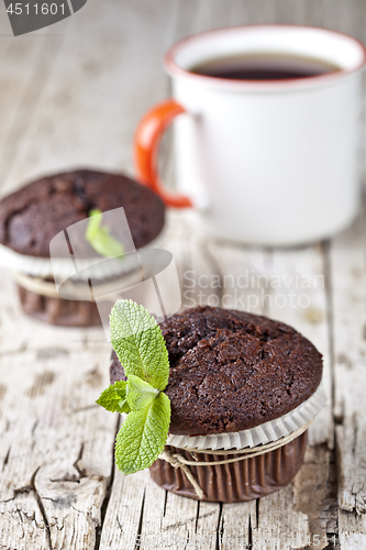 Image of Fresh dark chocolate muffins with mint leaves and cup of tea on 