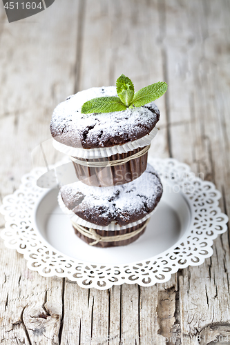 Image of Chocolate dark muffins with sugar powder and mint leaf on white 