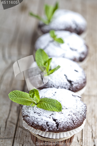 Image of Fresh chocolate dark muffins with sugar powder and mint leaf on 