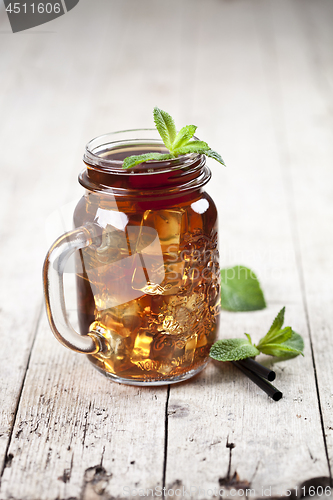 Image of Traditional iced tea with lemon, mint leaves and ice cubes in gl