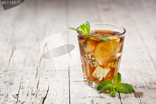 Image of Traditional iced tea with lemon, mint leaves and ice in glass on