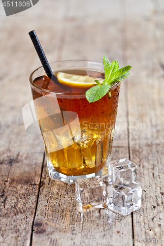 Image of Traditional iced tea with lemon, mint leaves and ice cubes in gl