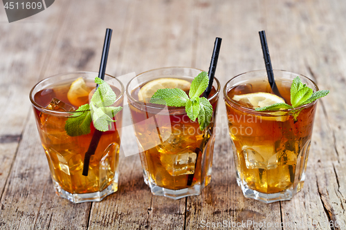 Image of Traditional iced tea with lemon, mint leaves and ice cubes in gl