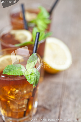 Image of Traditional iced tea with lemon, mint leaves and ice cubes in gl