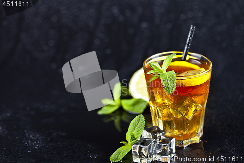 Image of Traditional iced tea with lemon, mint leaves and ice cubes in gl