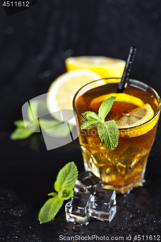 Image of Traditional iced tea with lemon, mint leaves and ice cubes in gl