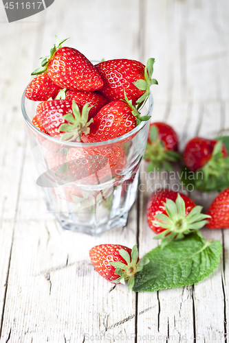 Image of Organic red strawberries glass and mint leaves on rustic wooden 