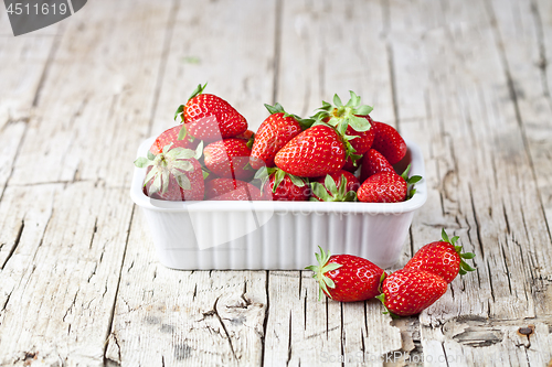 Image of Fresh red strawberries in white bowl and mint leaves on rustic w