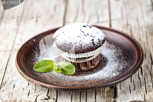 Image of Fresh chocolate dark muffin with sugar powder and mint leaf on b