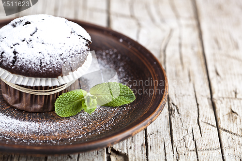 Image of Fresh chocolate dark muffin with sugar powder and mint leaf on b