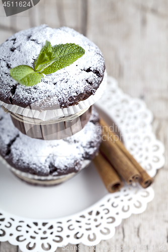 Image of Chocolate dark muffins with sugar powder, cinnamon sticks and mi