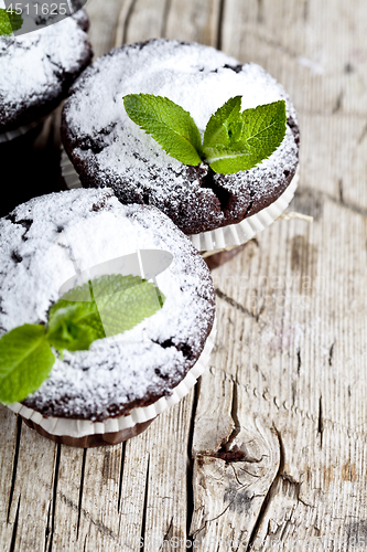 Image of Fresh chocolate dark muffins with sugar powder and mint leaf on 