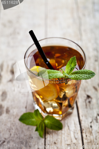Image of Traditional iced tea with lemon, mint leaves and ice cubes in gl