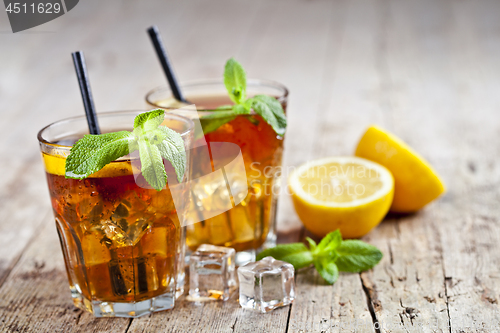 Image of Traditional iced tea with lemon, mint leaves and ice cubes in gl