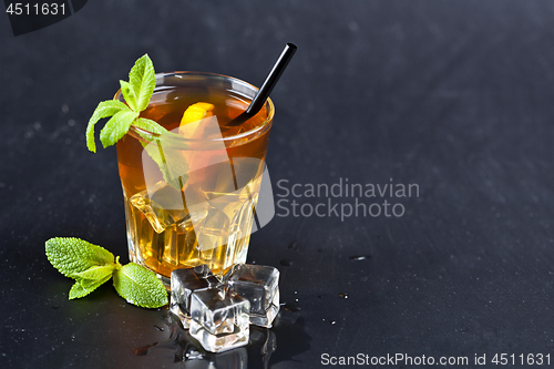 Image of Traditional iced tea with lemon, mint leaves and ice cubes in gl