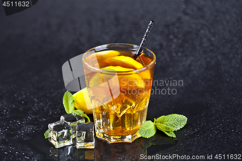 Image of Traditional iced tea with lemon, mint leaves and ice cubes in gl