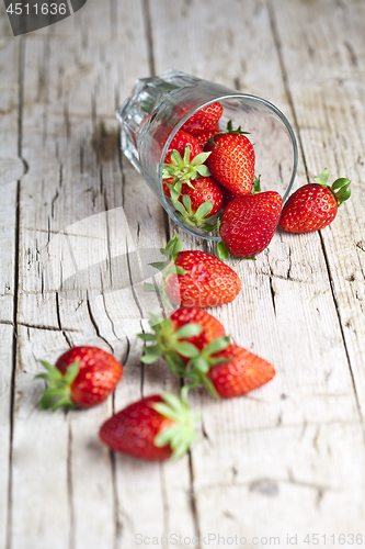Image of Organic red strawberries in glass on rustic wooden background.