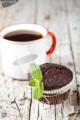 Image of Fresh dark chocolate muffin with mint leaves and cup of coffee o