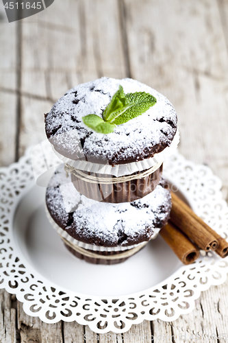 Image of Chocolate dark muffins with sugar powder, cinnamon sticks and mi