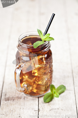 Image of Traditional iced tea with lemon, mint leaves and ice cubes in gl