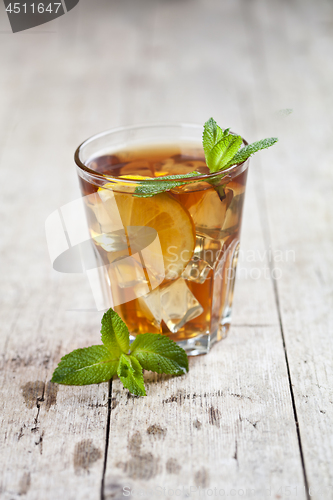 Image of Traditional iced tea with lemon, mint leaves and ice in glass on