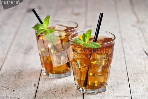 Image of Traditional iced tea with lemon, mint leaves and ice cubes in tw