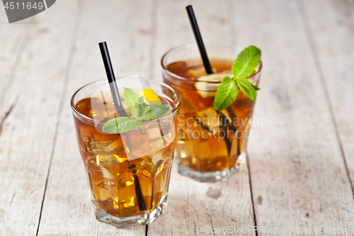Image of Traditional iced tea with lemon, mint leaves and ice cubes in tw