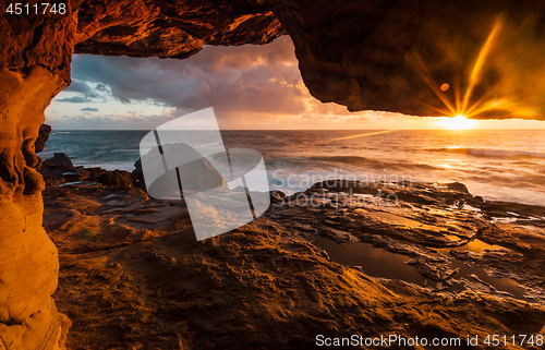 Image of Coastal rock tunnels to cliff ledges with early morning sunlight