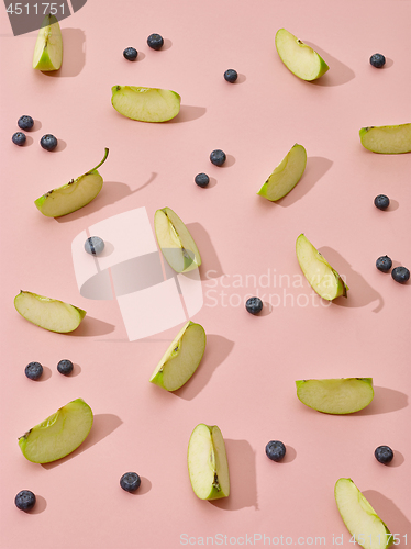 Image of apple pieces and blueberries on pink background