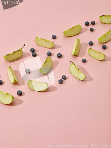 Image of apple pieces and blueberries on pink background