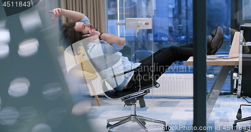 Image of businessman sitting with legs on desk