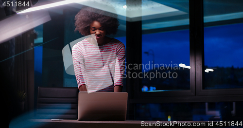 Image of black businesswoman using a laptop in night startup office