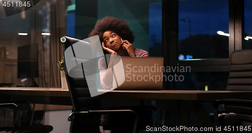 Image of black businesswoman using a laptop in night startup office