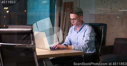 Image of man working on laptop in dark office