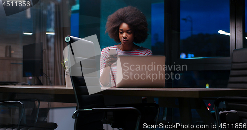 Image of black businesswoman using a laptop in night startup office