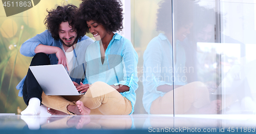 Image of multiethnic couple using a laptop on the floor