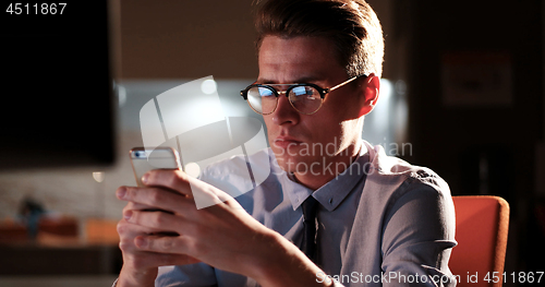 Image of man using mobile phone in dark office